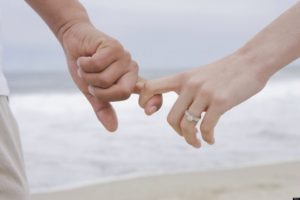 married couple holding hands on beach